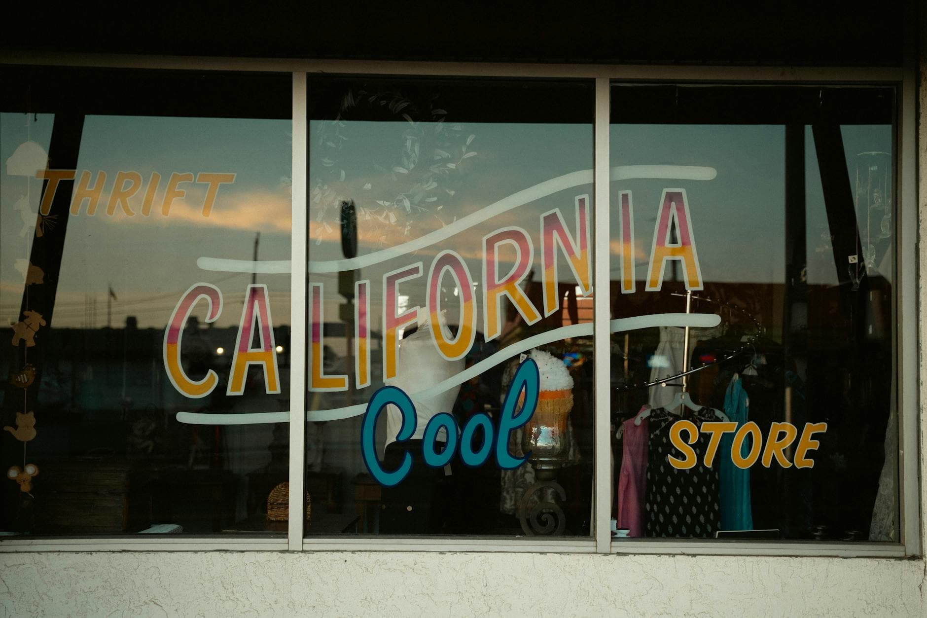 Vintage shop window with retro California thrift store signage and colorful display.