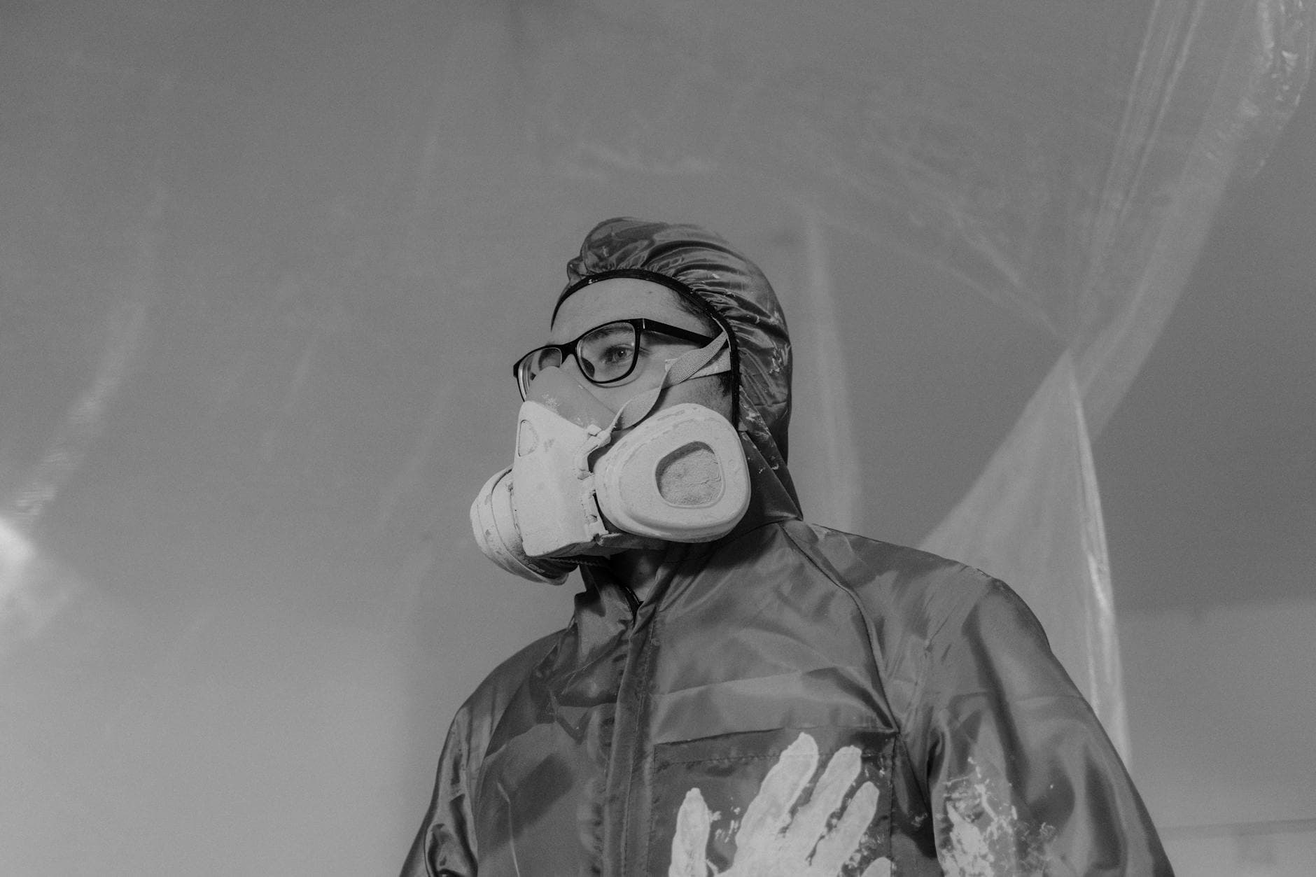 Worker wearing a gas mask and safety gear in a monochrome setting, emphasizing protection and safety.
