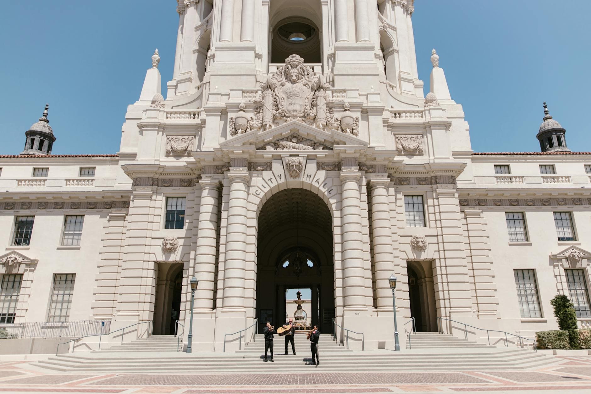 Mariachi band playing in front of the iconic Pasadena City Hall on a sunny day.